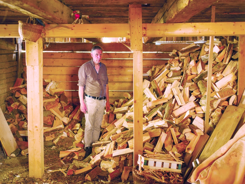 Leo Bäumler, who uses his wood stove to heat his house and cook meals, in his woodshed near Weiden, Germany. — The New York Times