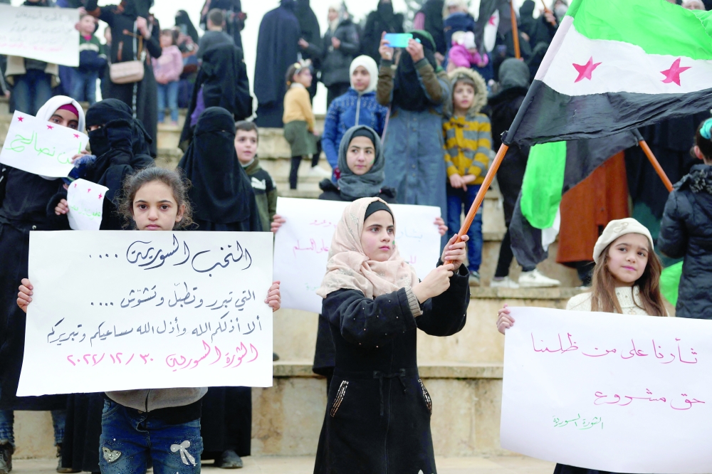 Children raise placards as they rally against a potential rapprochement between Ankara and the Syrian regime in the northwestern city of Idlib. - AFP