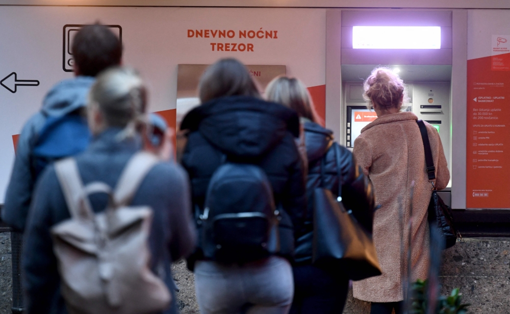 Clients wait in line to withdraw cash at a bank in the center of Zagreb on December 30, 2022, as EURO becomes Croatia's official currency on January 1, 2023.