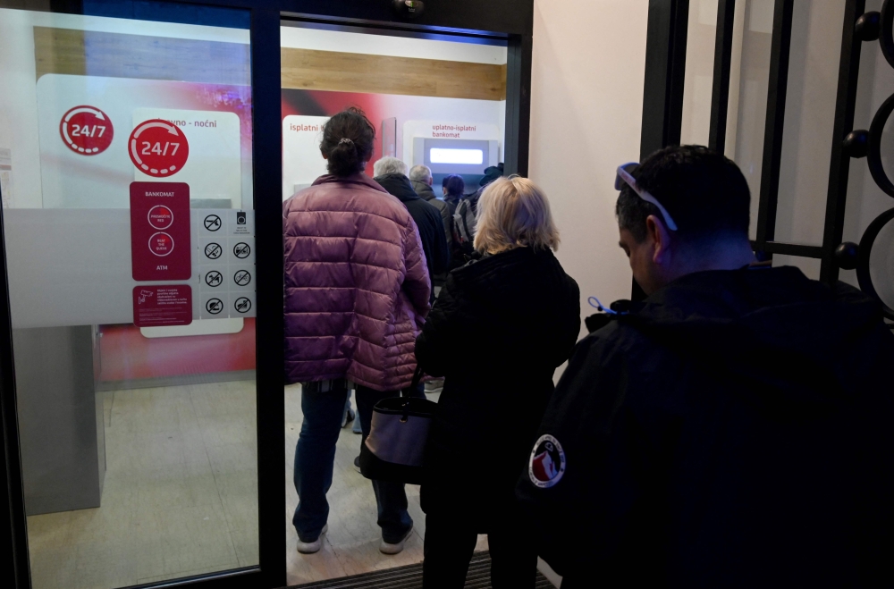 Clients wait in line to withdraw cash at a bank in the center of Zagreb on December 30, 2022, as EURO becomes Croatia's official currency on January 1, 2023.