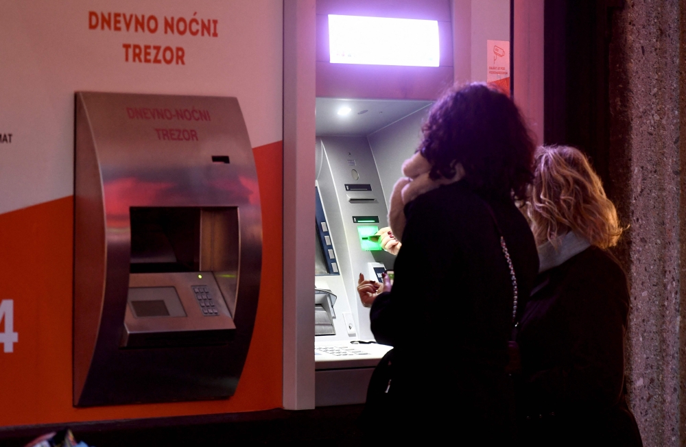 Clients wait in line to withdraw cash at a bank in the center of Zagreb on December 30, 2022, as EURO becomes Croatia's official currency on January 1, 2023.