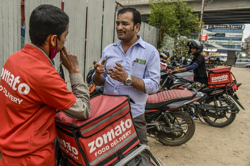 Shaik Salauddin, right, who has persuaded tens of thousands of delivery app drivers like himself to unionize, speaks to a driver in Hyderabad, India, Dec. 1, 2022.   (Atul Loke/The New York Times)