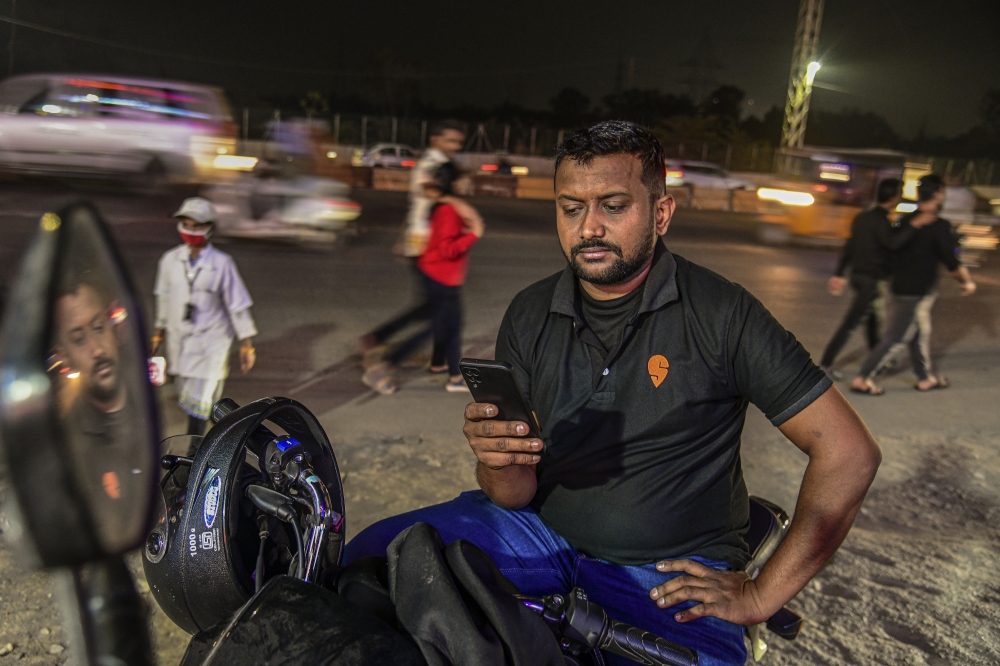 Ankit Bhatt, a delivery driver for Swiggy, checks his account status in the app in Hyderabad, India, Dec. 1, 2022. (Atul Loke/The New York Times)