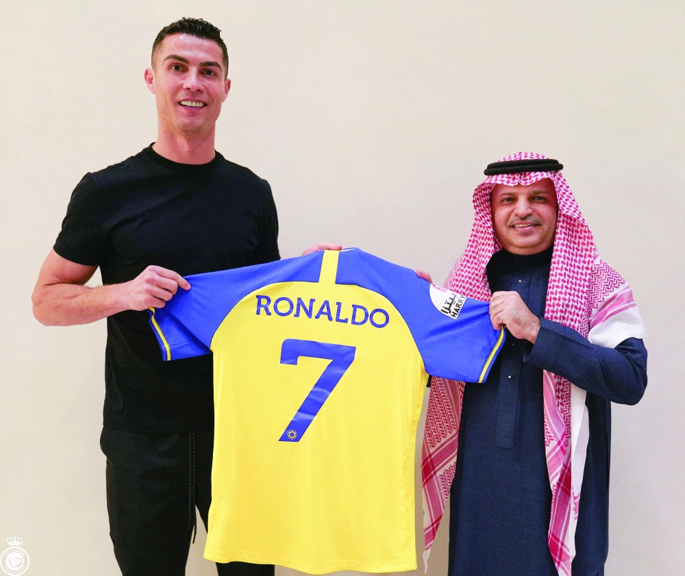 Portuguese soccer player Cristiano Ronaldo along with Musalli Al-Muammar, president of the Saudi Arabian club Al-Nassr holds a shirt of the club after signing the contract that runs until 2025, in this undated handout photo in an unknown location. AL-NASSR FC/Handout via REUTERS.  ATTENTION EDITORS - THIS IMAGE HAS BEEN SUPPLIED BY A THIRD PARTY. MANDATORY CREDIT. NO RESALES. NO ARCHIVES REFILE - REMOVING LOCATION
