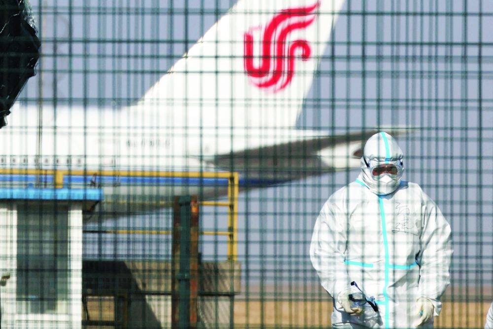 A worker in a protective suit walks near a plane of Air China airlines at Beijing Capital International Airport as coronavirus disease outbreaks continue in Beijing. - Reuters
