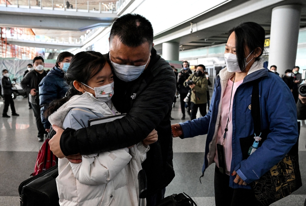 A passenger hugs her daughter at arrivals area for international flights at the Capital International Airport in Beijing on January 8, 2023.