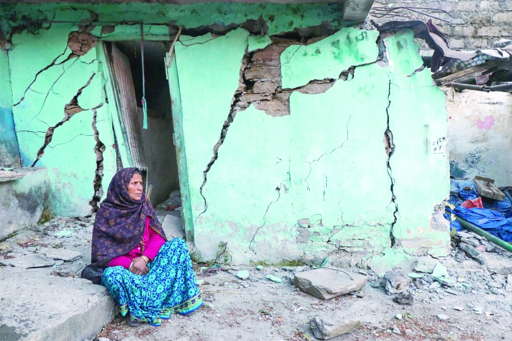 A woman sits beside a cracked wall of her house at Joshimath in Chamoli district of Uttarakhand. -- AFP