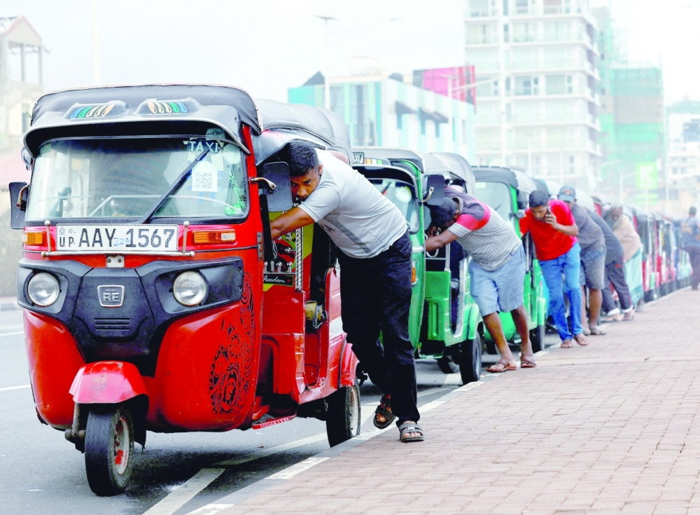Drivers push auto rickshaws in a line to buy petrol from a fuel station in Colombo. Sri Lanka is still reeling from months of food and fuel shortages that made daily life a misery for its 22 million people last year. -- Reuters