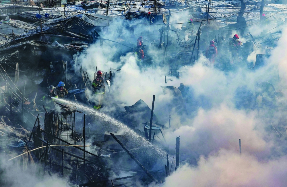 Firefighters try to extinguish a fire at the Guryong village, one of South Korea's last remaining slums, in southern Seoul. - AFP
