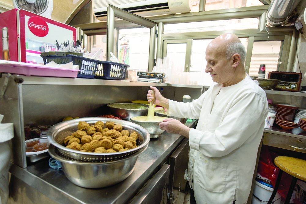 Ziyad Abu Shukri grinds his hummus by hand with a mortar and pestle, at a hole-in-the-wall shop in the Old City of Jerusalem, Oct. 12, 2022. (Tzachi Ostrovsky/The New York Times)