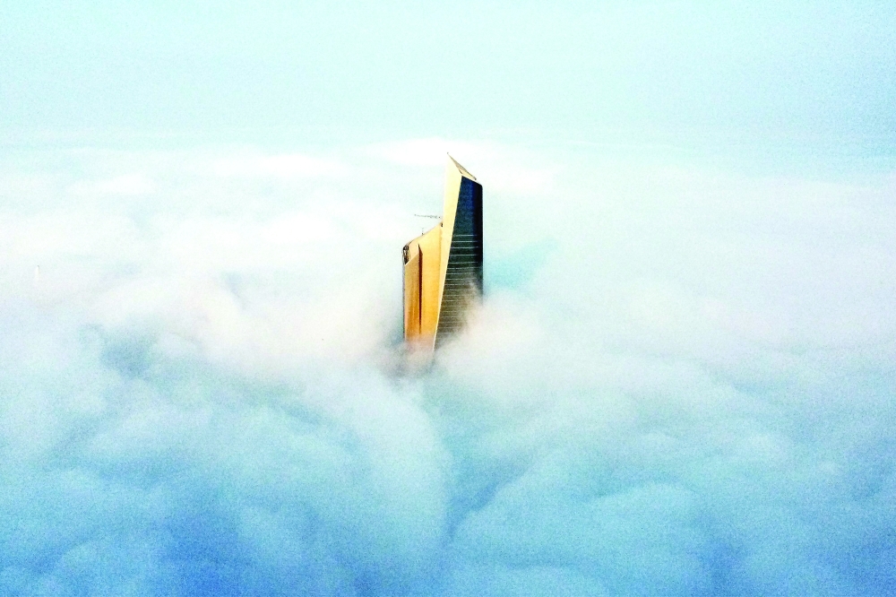 Aerial view shows the top of Al Hamra tower through heavy fog obscuring the rest of the skyline of Kuwait City on Monday. -- AFP