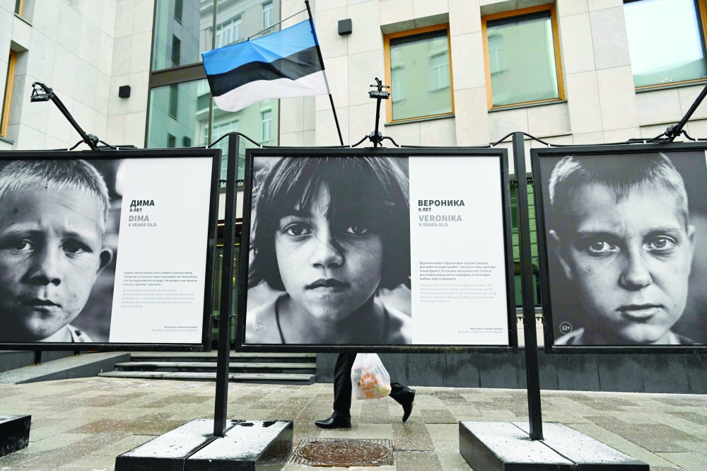 A person walks past the "Children of Donbass" open-air photo exhibition outside the Estonian Consulate in Moscow on Monday. - Reuters