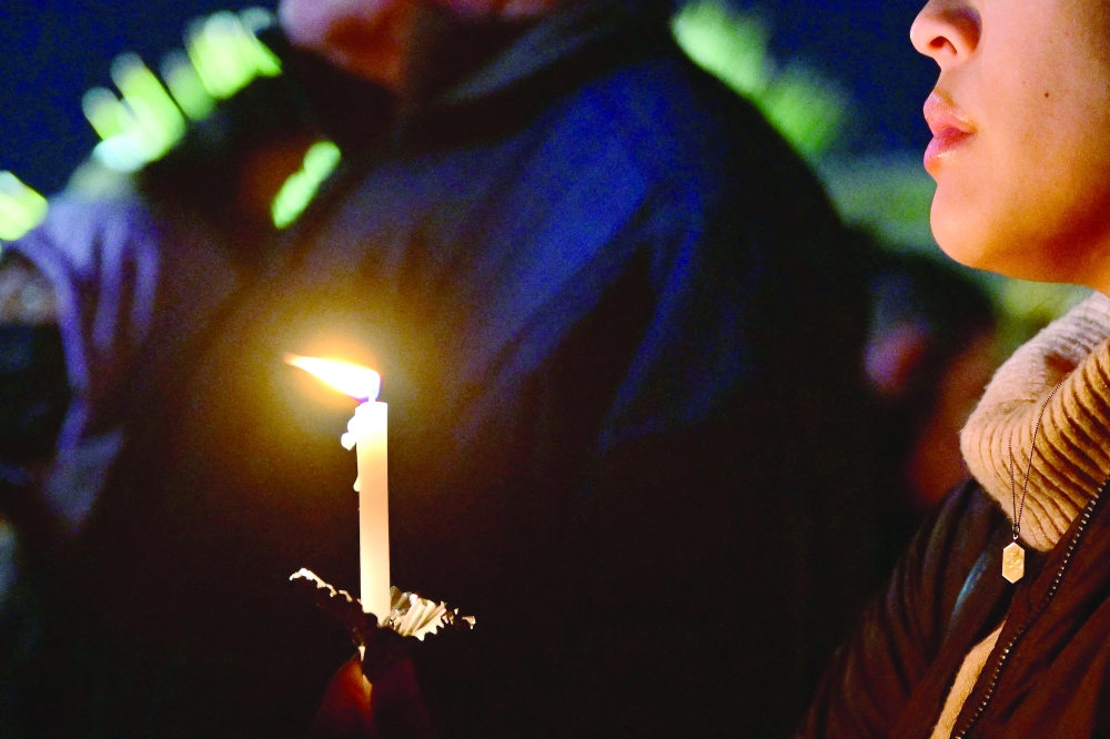 People attend a candle light vigil for victims of a mass shooting outside the City Hall in Monterey Park, California, on Monday. — AFP