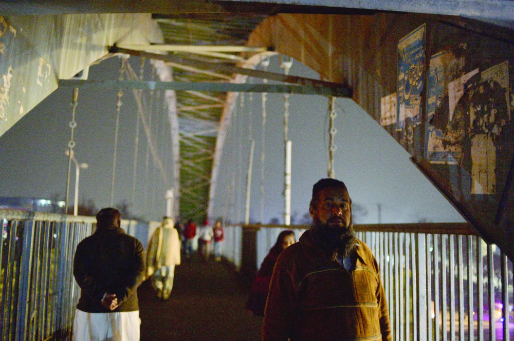 People walk across a bridge during a nationwide power outage in Islamabad on Tuesday. — AFP