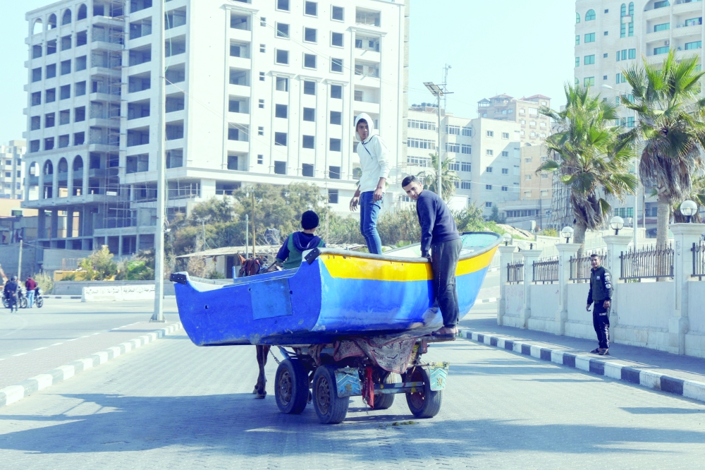Palestinians transport a fishing boat on a horse cart after being repaired at the seaport in Gaza City on Wednesday. - Reuters