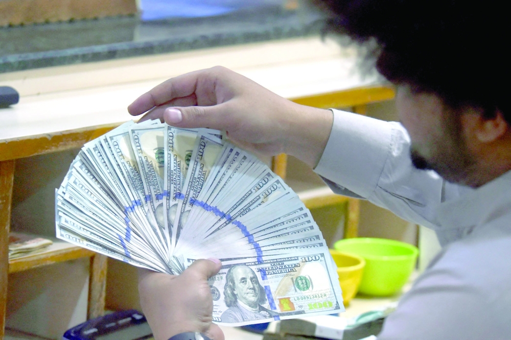 A dealer counts US dollars at a money exchange market in Karachi. - AFP