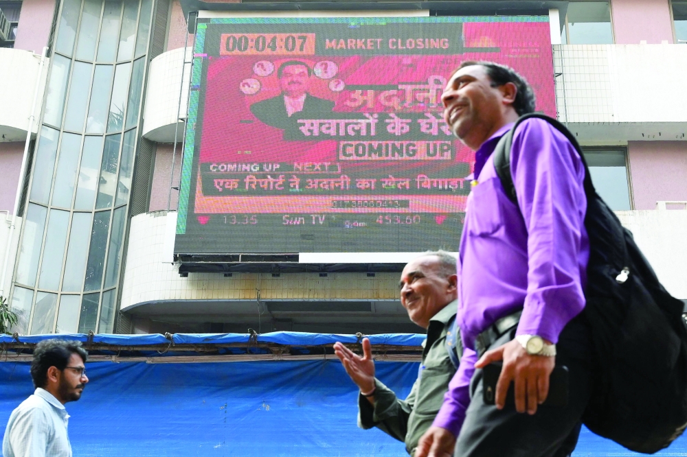 People walk past an electronic signage displaying news on the Adani Group at the Bombay Stock Exchange building in Mumbai. - AFP
 