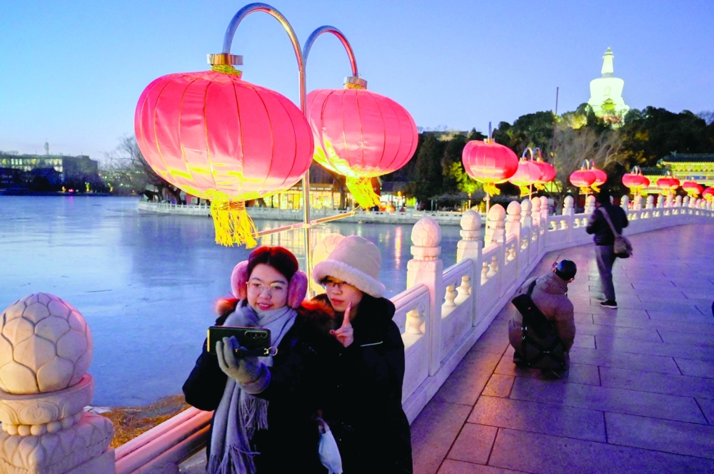 Visitors take pictures next to lanterns set up on a bridge for the lunar new year at a park in Beijing. - AFP



