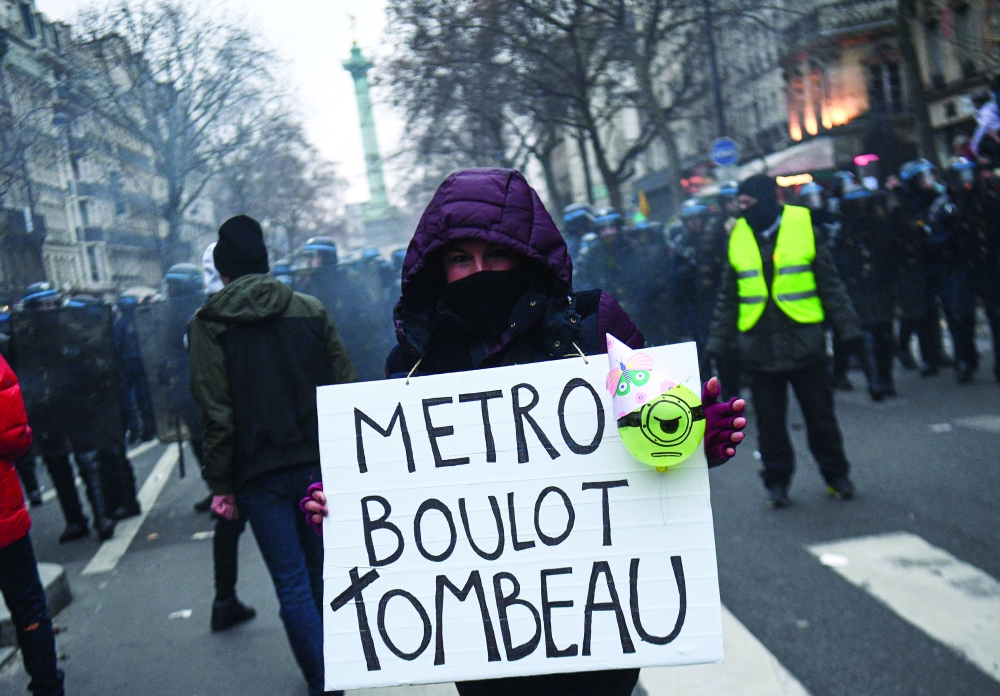 In this file photo taken on January 19, 2023 a demonstrator holds a sign reading 'Metro, job, tomb' during a rally as workers go on strike over French President's plan to raise the legal retirement age from 62 to 64 in Paris. -- AFP