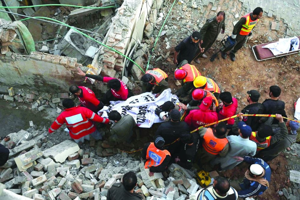 Rescue workers carry the remains of the blast victims from the debris of a damaged mosque in Peshawar on Monday. -- AFP