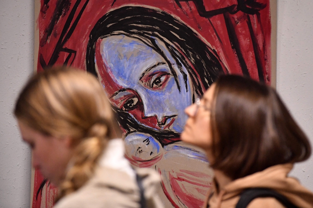 Women tour an exhibition of pacifist paintings by Yelena Osipova in Saint Petersburg. - AFP