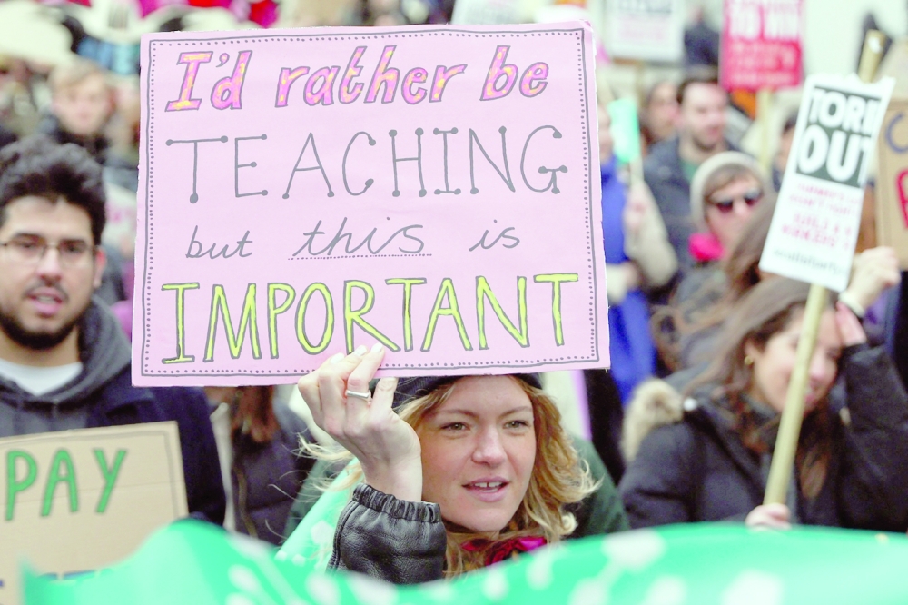 Teachers hold placards as they take part in a protest organised NEU and other affiliated trade unions in central London, on Wednesday. -- AFP