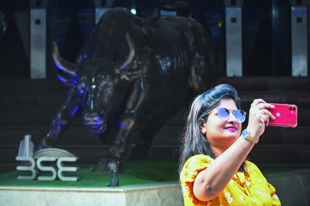 An onlooker takes a selfie next to the bronze bull beneath a digital broadcast showing India's Finance Minister Nirmala Sitharaman presenting the union budget outside the Bombay Stock Exchange (BSE) in Mumbai on Wednesday. - AFP