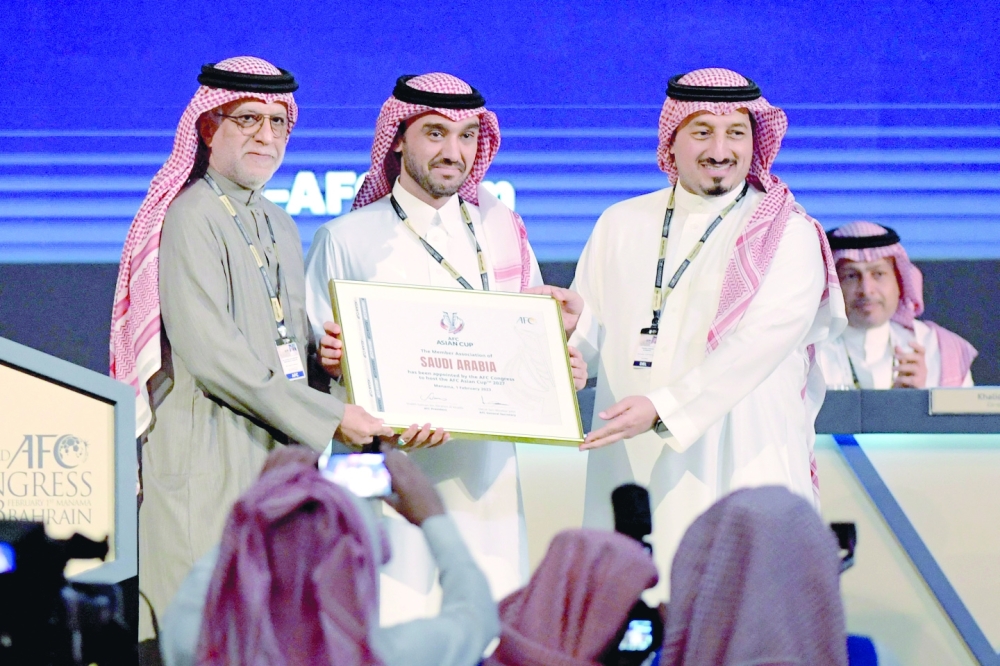 AFC President Salman bin Ibrahim al Khalifa (L) presents Saudi Arabia's Minister of Sports and Youth Abdulaziz bin Turki al Faisal al Saud (C) with a plaque, appointing Saudi Arabi as the host of the 2027 AFC Asian Cup, during the 33rd Asian Football Confederation (AFC) Congress at the Gulf Convention Centre in Manama on Wednesday. -- AFP