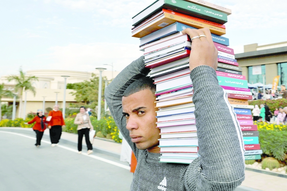 A boy carries a load of books at the 54th Cairo International Book Fair in Cairo. - AFP


