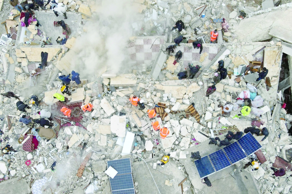 This aerial view shows residents helped by bulldozers, searching for victims and survivors in the rubble of collapsed buildings, in the town of Sarmada in the northwestern Syrian Idlib province, early on Monday. - AFP