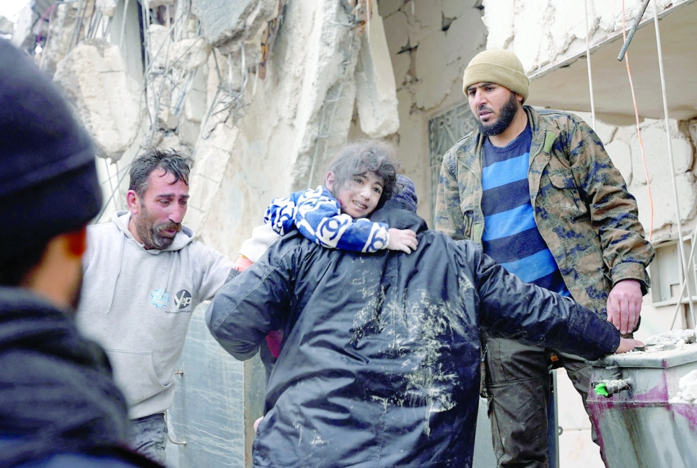 Residents retrieve a small child from the rubble of a collapsed building following an earthquake in the town of Jandaris, in the countryside of Syria's northwestern city of Afrin. - AFP