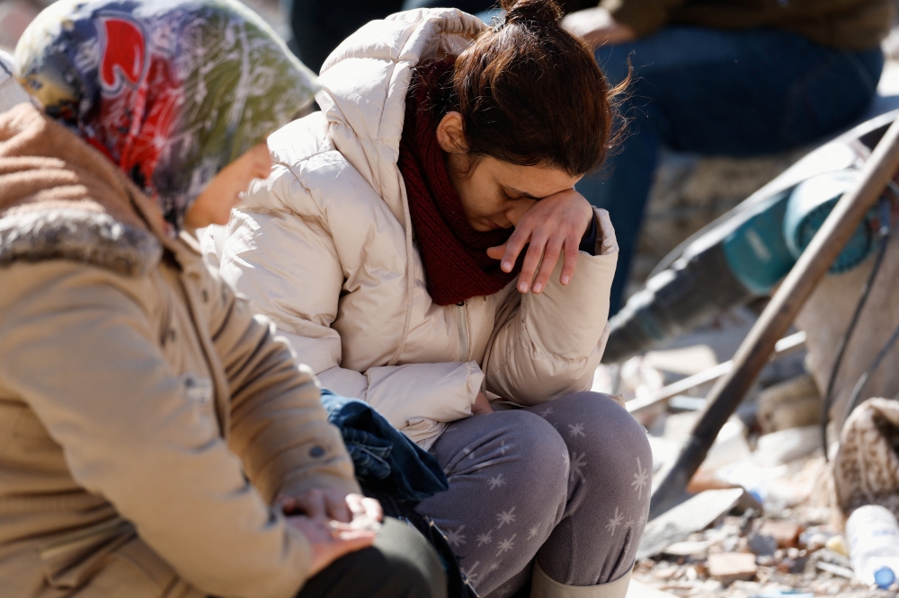 A woman reacts next to a damaged building, in the aftermath of a deadly earthquake, in Kirikhan, Turkey February 9, 2023. 
