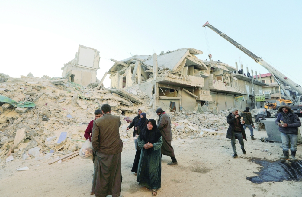 People walk past damaged buildings Jandaris, Syria, on Thursday.  — Reuters