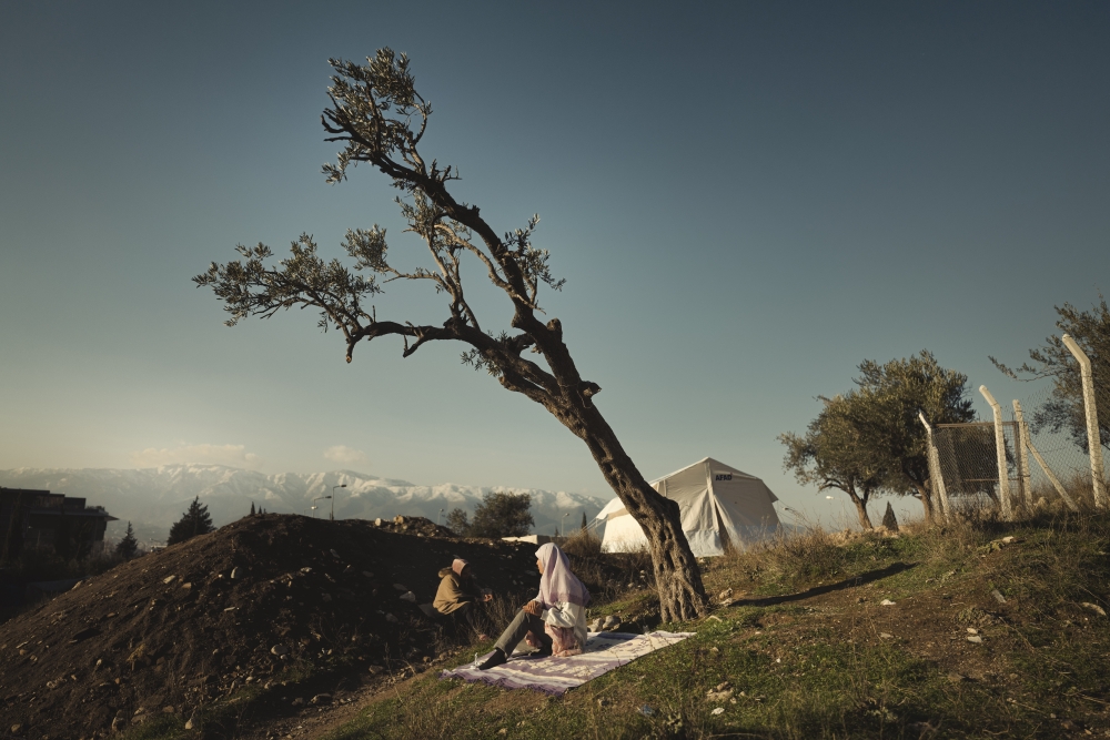 A displaced woman rests under an olive tree on a hillside in Antakya, , in Hatay Province, Turkey, three days after the earthquake, on Thursday, Feb. 9, 2023. (Emily Garthwaite/The New York Times)