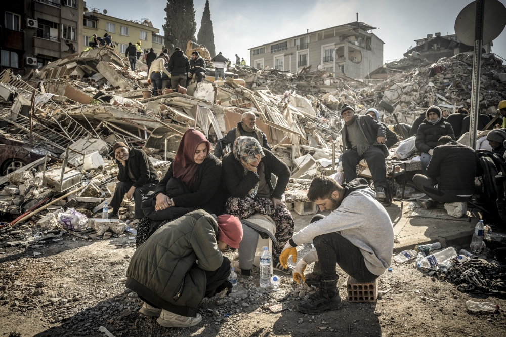 Displaced residents sit near their collapsed home as rescue operations continue in Antakya, Turkey on Thursday, Feb. 9, 2023. (Sergey Ponomarev/The New York Times)