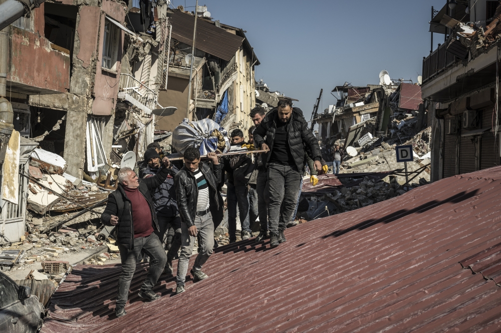 Men carry the body of an earthquake victim from the rubble of collapsed buildings in Antakya, Turkey on Thursday, Feb. 9, 2023. (Sergey Ponomarev/The New York Times)