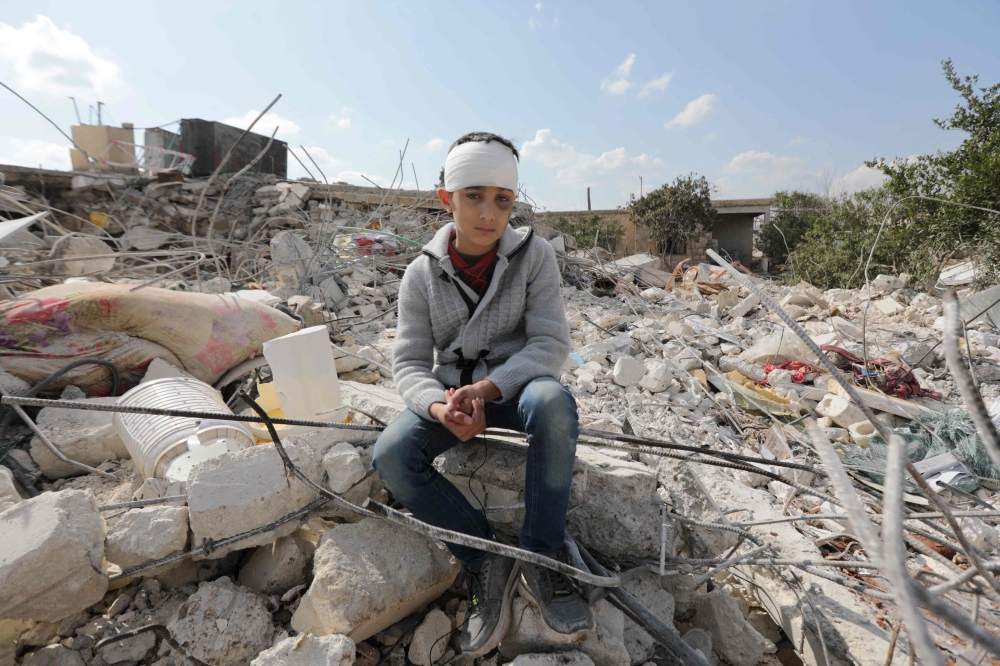 A Syrian boy, who lost his family and was also wounded as a result of the deadly earthquake hit Turkey and Syria, sits amid the rubble of his family home in the town of Jindayris, in the rebel-held part of Syria's Aleppo province on February 11, 2023.  (Photo by Bakr ALKASEM / AFP)

