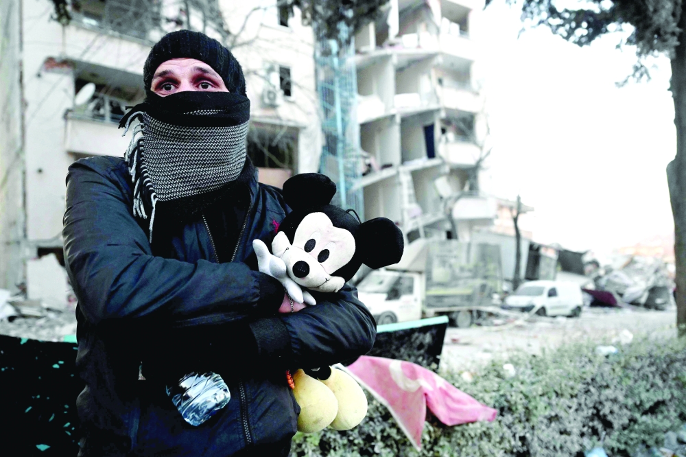 A man holds a Micky Mouse doll which belongs to his newphew in Kahramanmaras. -- AFP