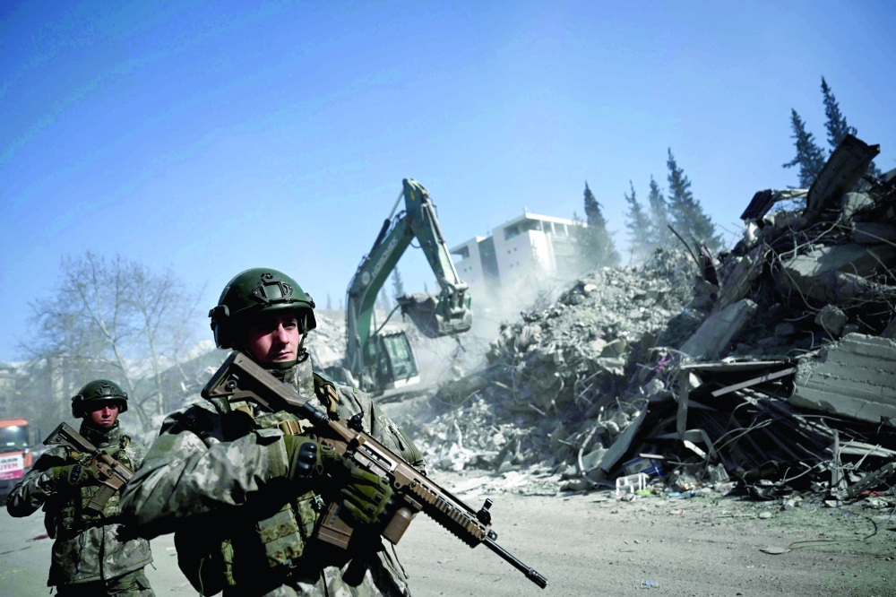 Turkish soldiers patrol next to collapsed buildings in Kahramanmaras. - AFP