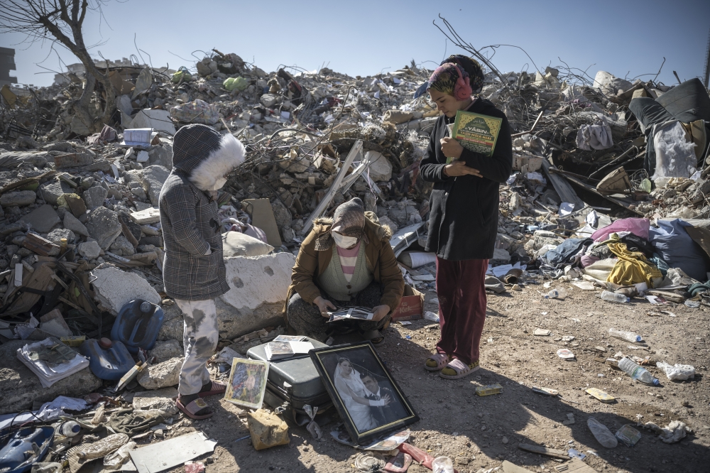 A woman and her children search for family photos amid the rubble in Kahramanmaras, Turkey, Feb. 13, 2023. (Sergey Ponomarev/The New York Times)