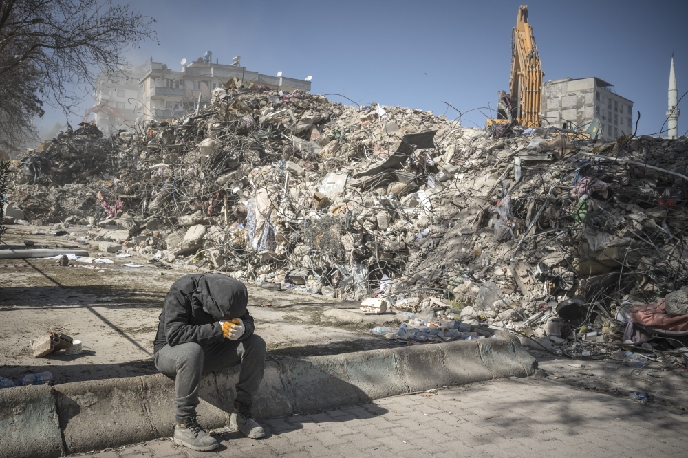 A man pauses near rubble from buildings in Kahramanmaras, Turkey, Feb. 13, 2023. (Sergey Ponomarev/The New York Times)