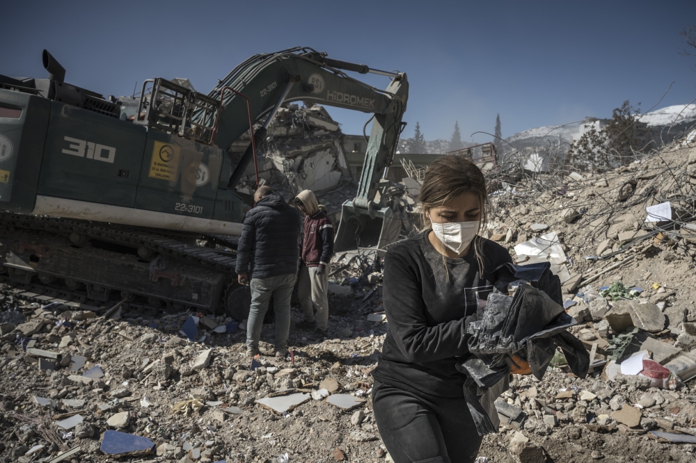 A woman removes her belongings from the rubble in Kahramanmaras, Turkey, Feb. 13, 2023.. (Sergey Ponomarev/The New York Times)