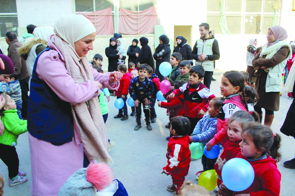 Unicef volunteers play with children at a makeshift shelter in a school run by Unicef where psychological first aid is provided in Aleppo. - Reuters