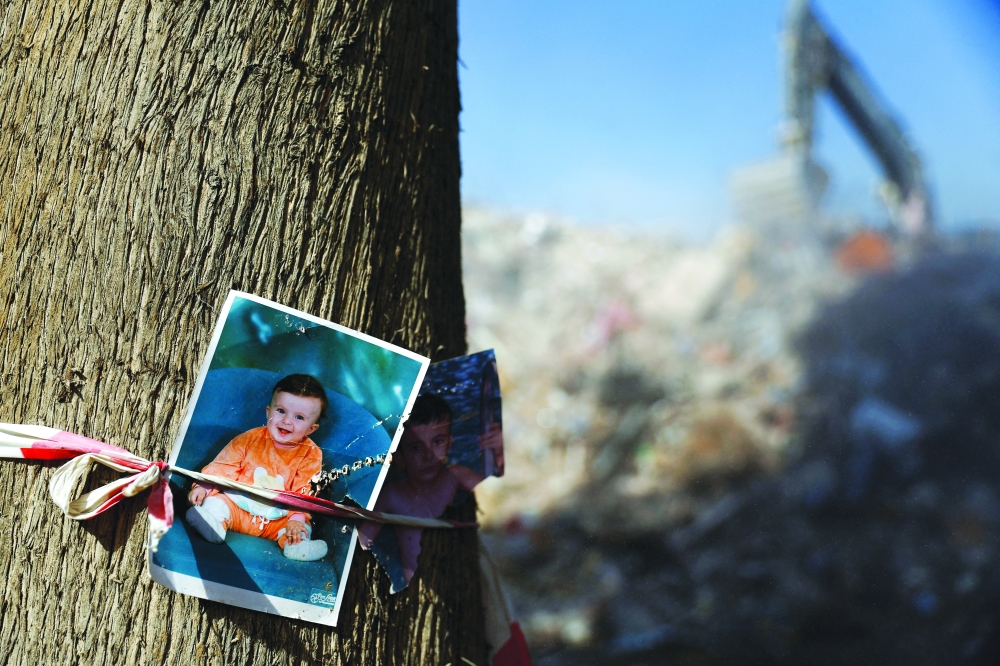 Photographs of children are fixed to a tree near rubble, in the aftermath of a deadly earthquake in Kahramanmaras, Turkiye. - Reuters