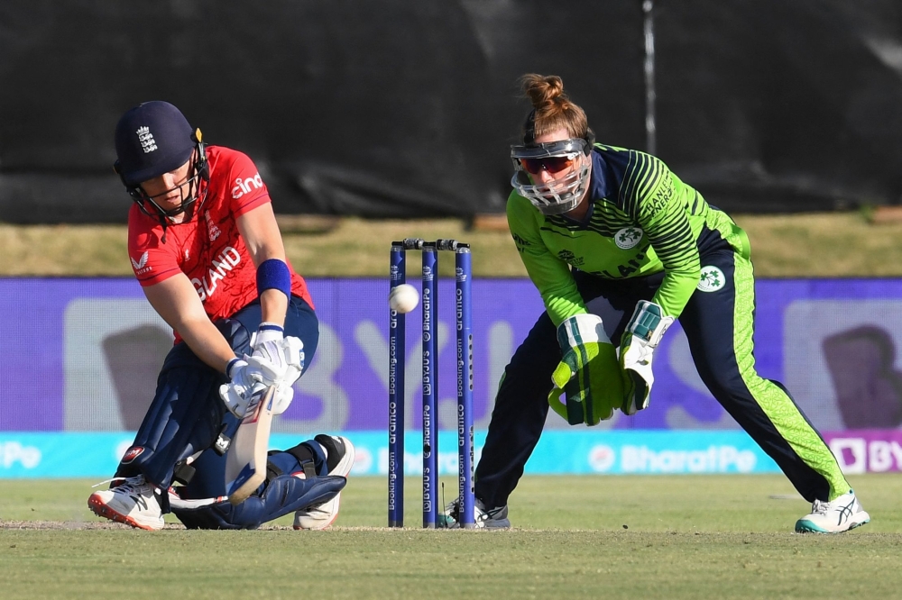 TOPSHOT - England's Amy Jones (L) plays a shot as Ireland's wicketkeeper Mary Waldron (R) looks on during the Group B T20 women's World Cup cricket match between Ireland and England at Boland Park in Paarl on February 13, 2023. (Photo by Rodger Bosch  / AFP)

