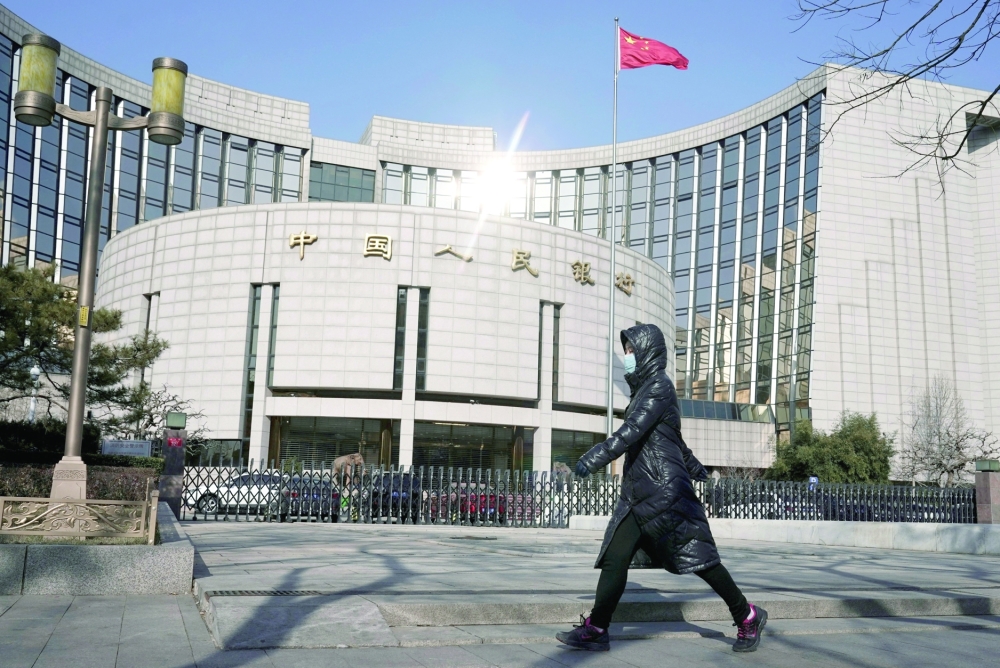 A woman walks past the headquarters of the People's Bank of China, the central bank, in Beijing, China. — Reuters