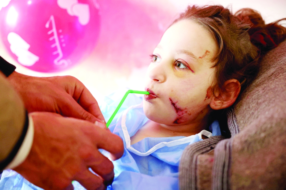 A volunteer feeds Syrian girl Hanaa Sharif (8), the only survivor of her family following the earthquake as she lies in a hospital bed in Maarat Misrine, in Syria's northern Idlib province. - AFP