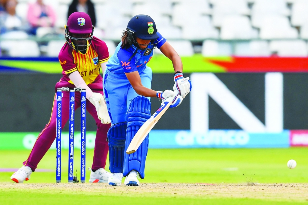 India's Harmanpreet Kaur (R) plays a shot as West Indies' wicketkeeper Rashada Williams (L) looks on during the Group B T20 women's World Cup cricket match between West Indies and India at Newlands Stadium in Cape Town on February 15, 2023. (Photo by Rodger Bosch  / AFP)

