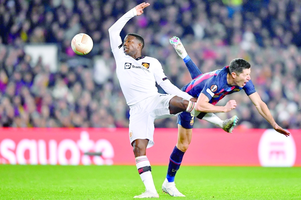 Manchester United's Dutch defender Tyrell Malacia (L) fights for the ball with Barcelona's Polish forward Robert Lewandowski during the UEFA Europa League round of 32 first-leg football match between FC Barcelona and Manchester United at the Camp Nou stadium in Barcelona, on February 16, 2023. (Photo by Pau BARRENA / AFP)

