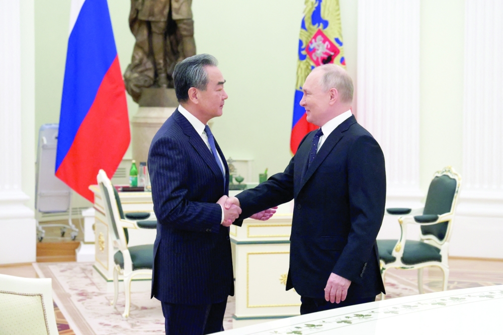 Russia's President Vladimir Putin shakes hands with China's Director of the Office of the Central Foreign Affairs Commission Wang Yi during a meeting in Moscow on Wednesday. — Reuters 